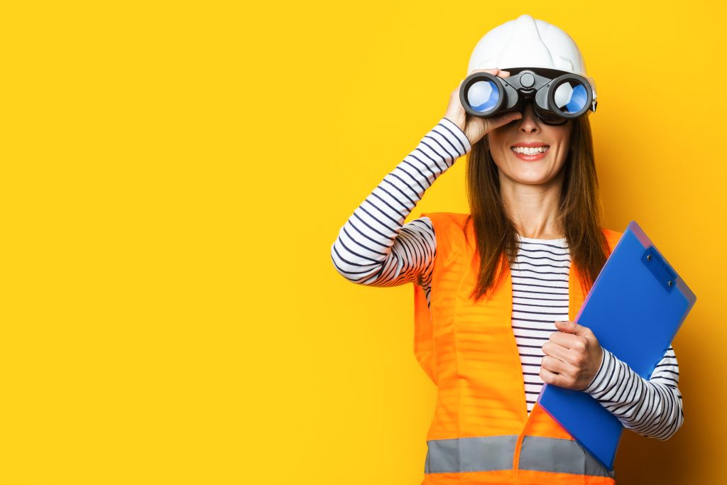 Young Woman In Signal Vest And Construction Helmet Looking Throu